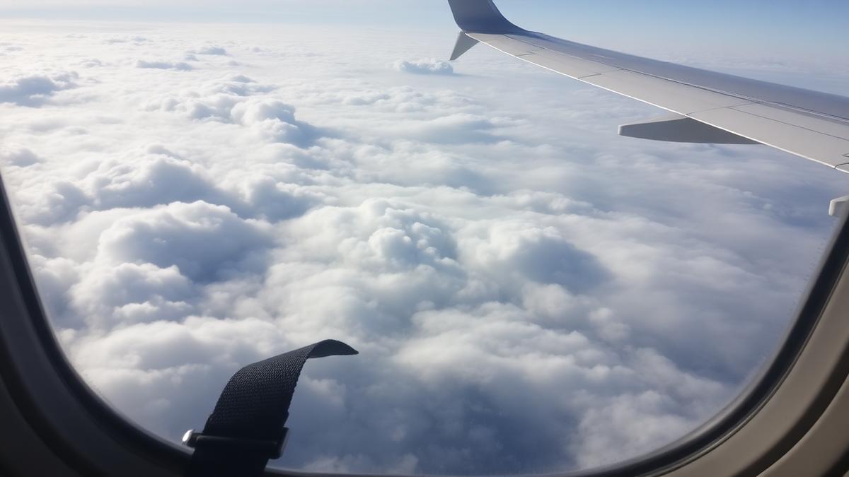 Uitzicht vanuit een vliegtuigraam op wolkenvelden met vastgemaakte gordel
