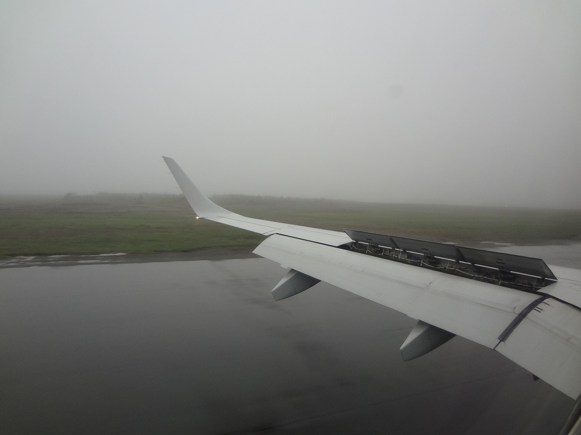 Vliegtuig landt op een natte landingsbaan tijdens regenachtig weer